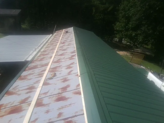 Old rusted panels beside newly installed green metal roofing — Wind Damage Roof Repair by Roofing Brothers in Mutual