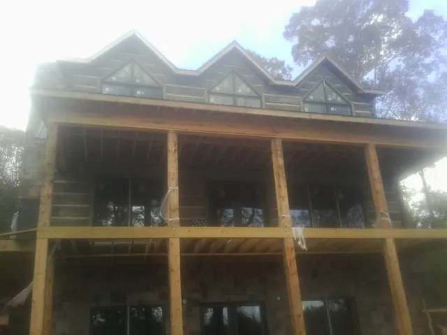 Dormers and porch framing on a large log home under construction — Roof Coating work by our crew in Mutual