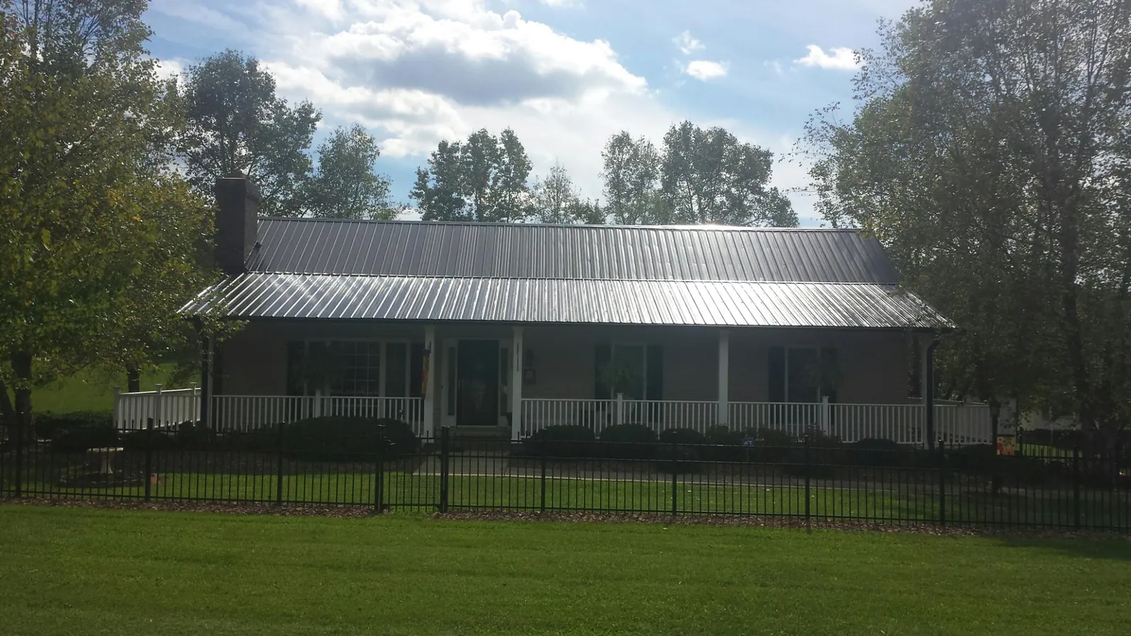 Gray metal roof on a brick ranch with a full width front porch — Gutter Guard Installation work by our crew in Mutual