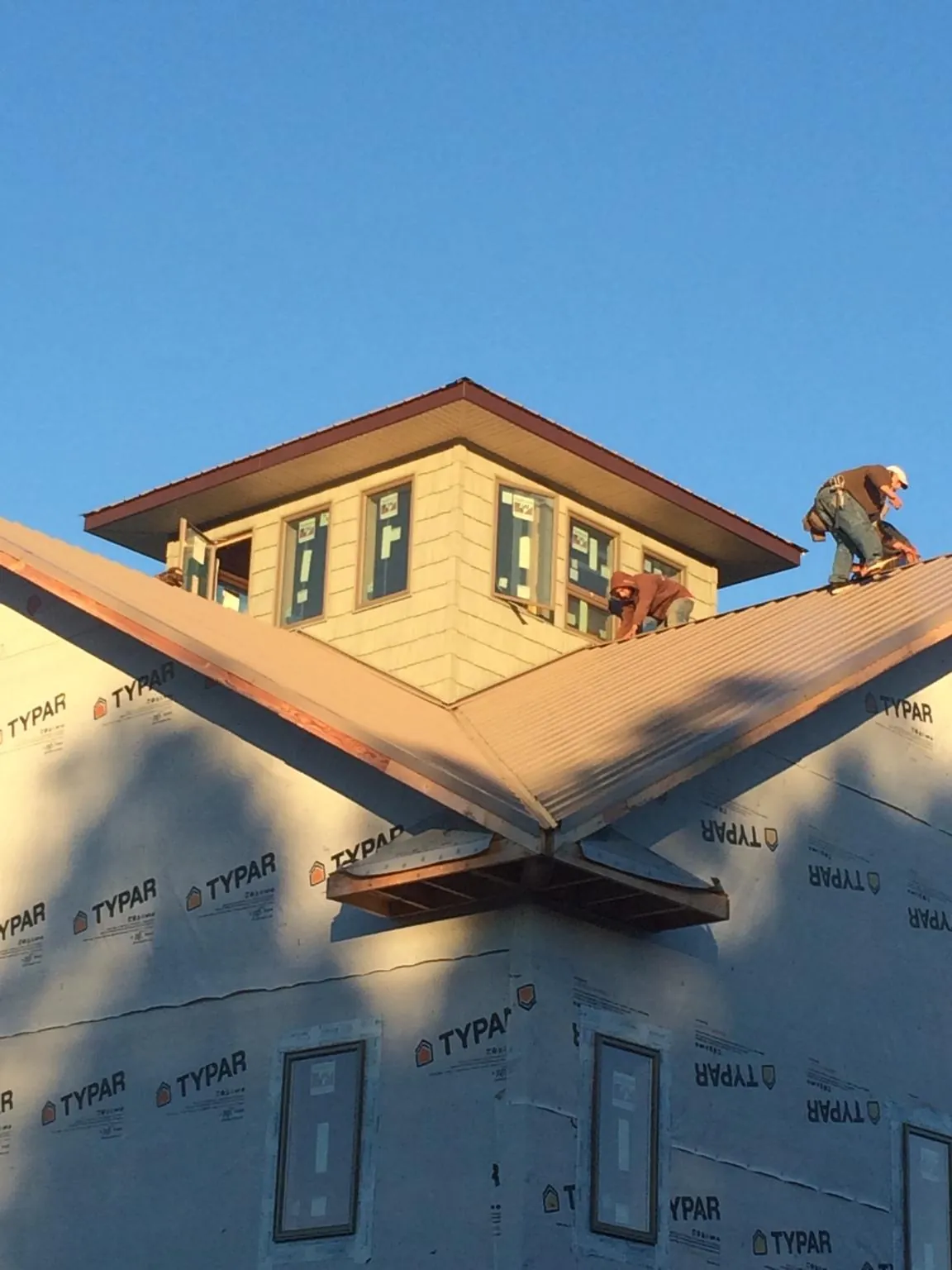 Roofers working around a rooftop cupola on a new metal roof at sunset — Roof Waterproofing in Mutual by Roofing Brothers